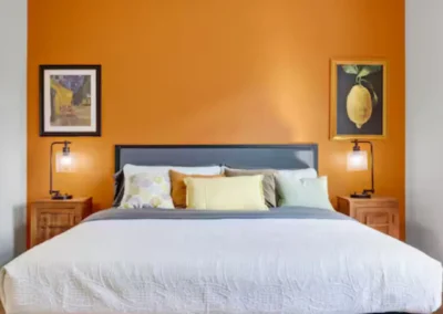 Bedroom with orange accent wall and queen bed